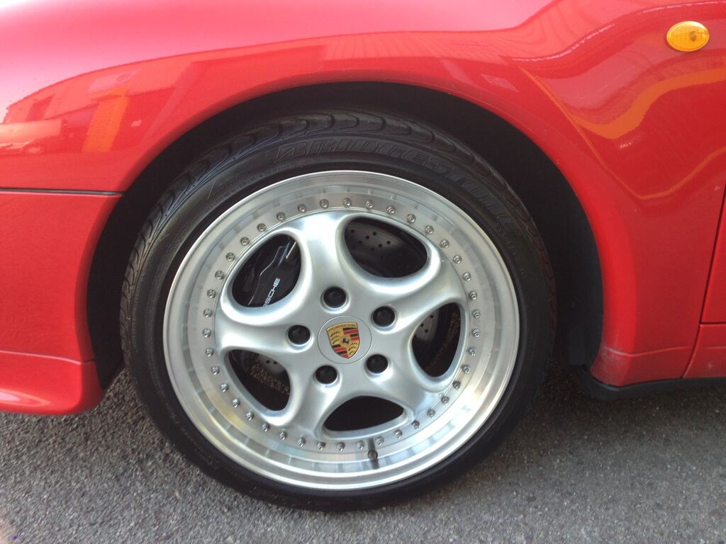 Refurbished alloy wheel on a red Porsche